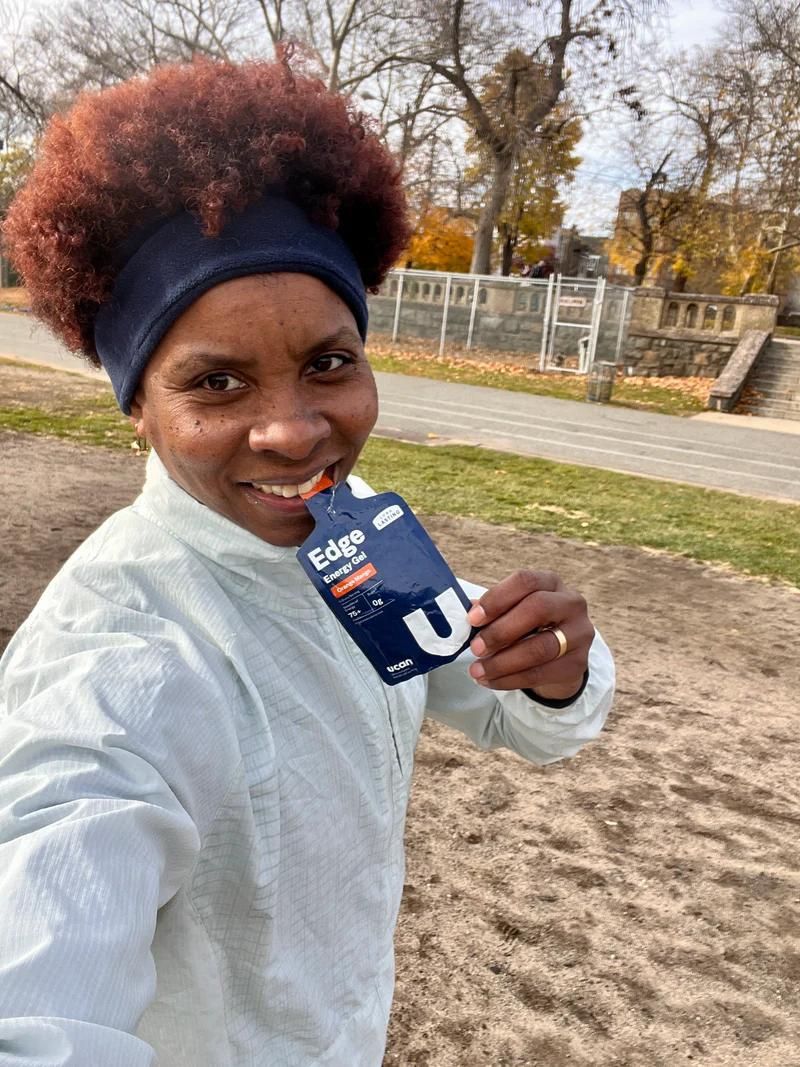 Woman drinking an Orange Mango Edge energy gel while on a run.