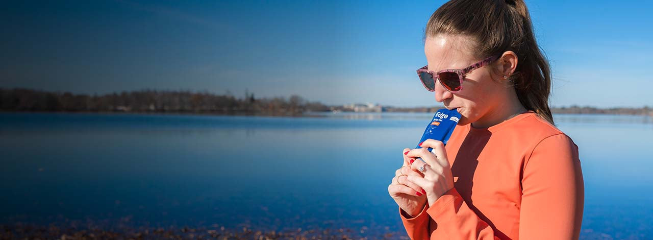 Woman drinking a no sugar UCAN Edge Energy Gel.