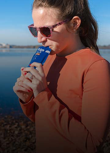 Woman drinking a no sugar UCAN Edge Energy Gel.